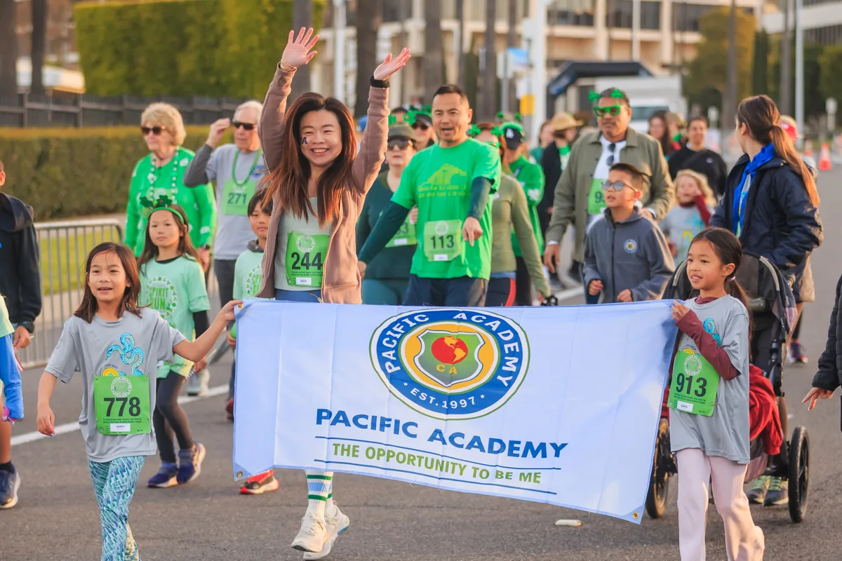 Pacific Academy students and families walking the Family Mile together behind their banner at the Newport Spirit Run