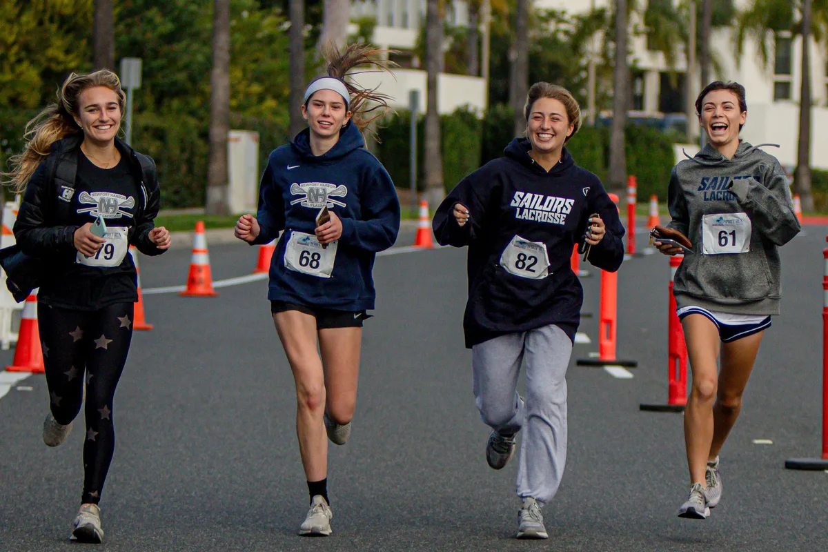 Four young runners in Newport Harbor Sailors sweatshirts racing down the course at the Newport Spirit Run